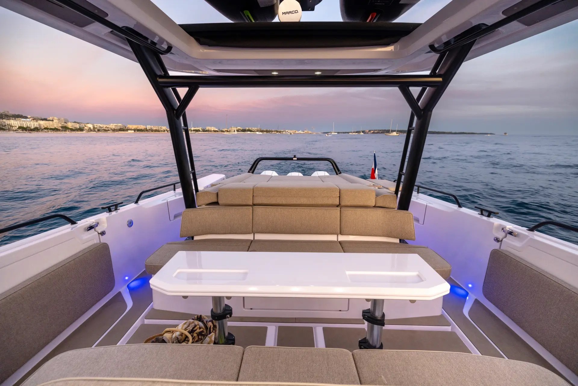 Aft deck of the Axopar 45 Cross Top with lounge seating and dining table at sunset